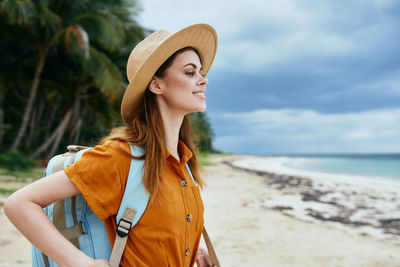 Young woman looking away at beach against sky