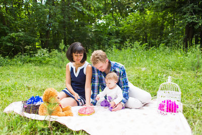 Friends sitting on grass against plants