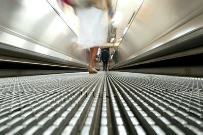 Low section of person walking on escalator