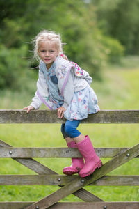 Portrait of cute girl climbing on wooden fence