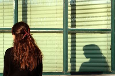 Rear view of woman standing against window