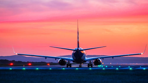 Airplane at airport runway during sunset