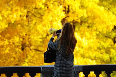 Rear view of woman photographing yellow umbrella