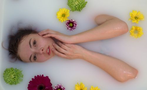 High angle portrait of woman lying in bathtub with flowers