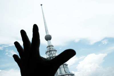 Low angle view of silhouette hand against tower