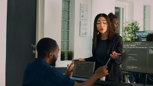 Side view of young woman using digital tablet while standing in office