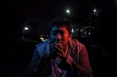 Portrait of young man smoking at night