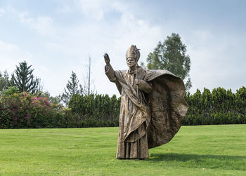 Statue on field against sky