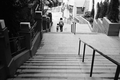 High angle view of mother and daughter walking on steps amidst buildings