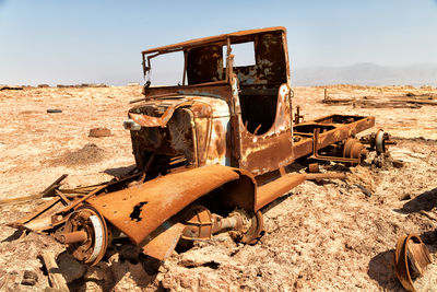 Old rusty machine on field against sky