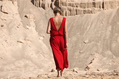 Rear view of woman with umbrella walking on sand