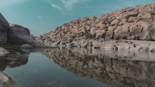 Rock formations by lake against sky