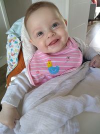 Portrait of cute baby girl on bed at home