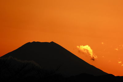 Silhouette mountain against orange sky