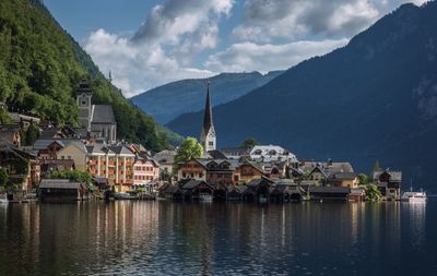 View of town by river against cloudy sky