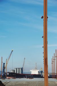 Cranes at harbor against sky