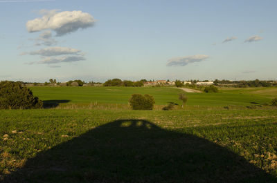 Scenic view of field against sky with a creative shadow of a car