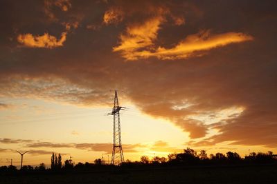 Low angle view of silhouette electricity pylon against sky during sunset