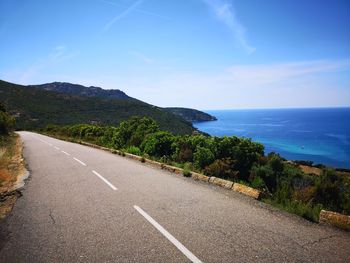 Road by sea against blue sky