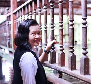 Portrait of young woman standing by wooden railing