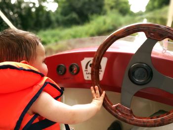 Boy touching steering wheel while travelling in boat