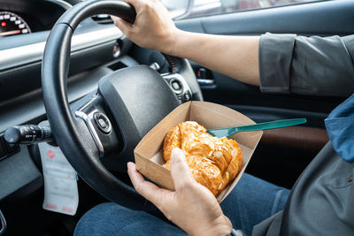 Midsection of woman holding food while driving