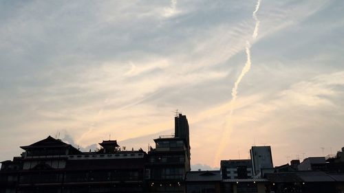 Buildings in city against cloudy sky