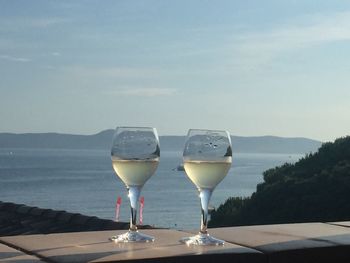 Wine glass on table by mountain against sky