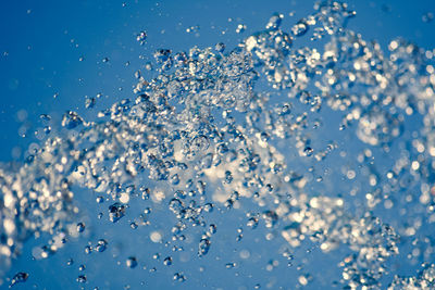 Close-up of wet glass against blue background