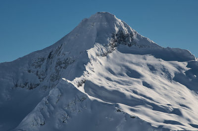 Scenic view of snowcapped mountains against clear blue sky