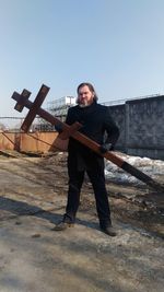 Full length portrait of man holding cross