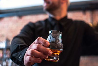 Midsection of man holding whiskey glass in bar