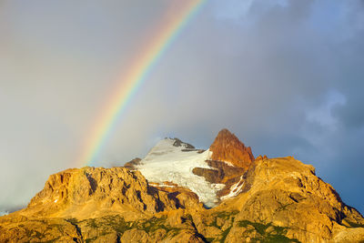 Scenic view of rainbow over mountains against sky