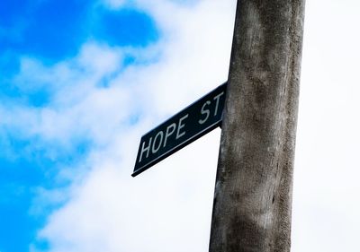 Low angle view of road sign against blue sky