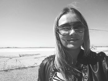 Portrait of mature woman wearing sunglasses standing at beach against sky