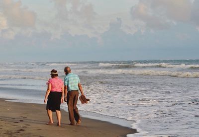 Rear view of couple walking on beach