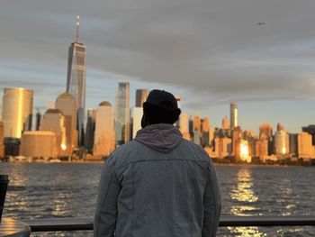 Rear view of man looking at sea against sky during sunset