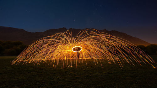 Man standing amidst illuminated wire wool at night