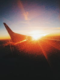 Airplane wing against sky during sunset