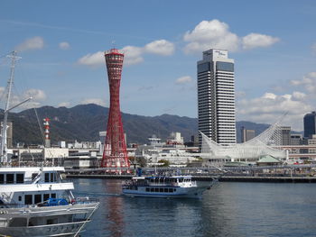 View of city at waterfront against cloudy sky