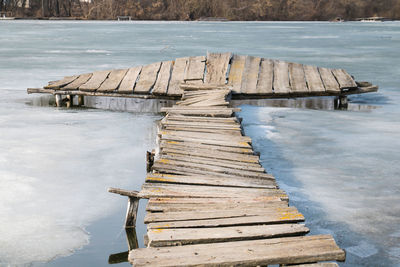 Wooden jetty in water against sky