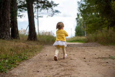 Rear view of woman walking on dirt road