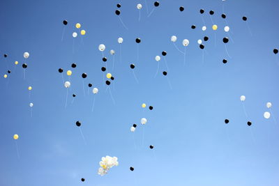 Low angle view of balloons flying against blue sky