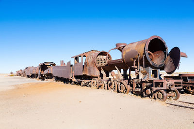 Old rusty train on desert against clear sky
