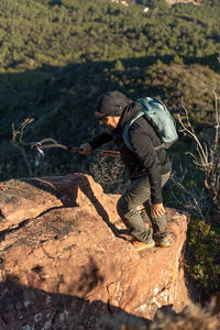 Middle-aged man climbs the mountain in the garraf natural park, supported by hiking poles.