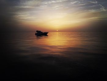 Silhouette boat sailing on sea against sky during sunset