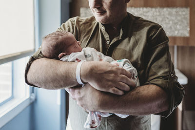 Father holding newborn boy wrapped in blankets in hospital