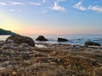 Rocks on beach against sky during sunset