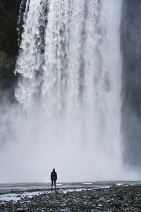 Rear view of man standing against waterfall