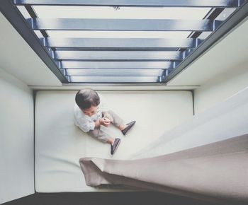 High angle view of baby boy sitting by window